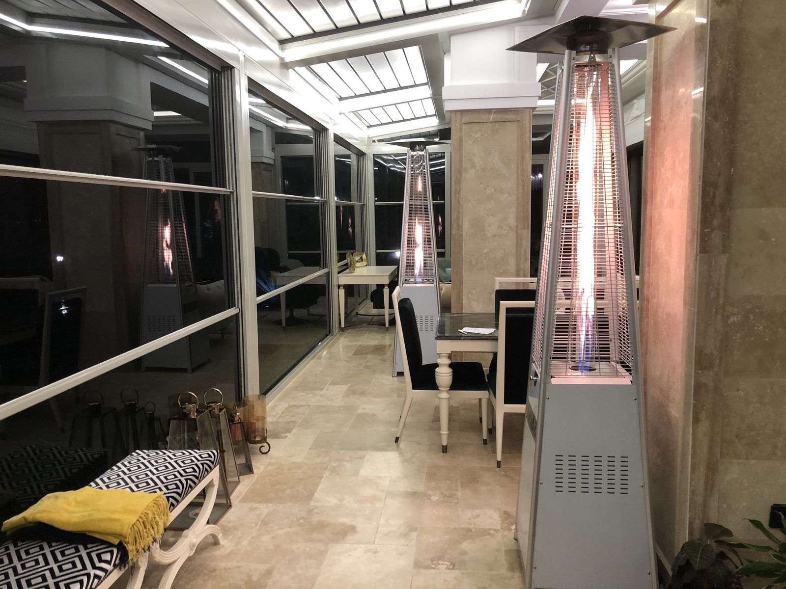 Restoran terasında sıra hâlinde kurulmuş piramit dış mekân ısıtıcıları